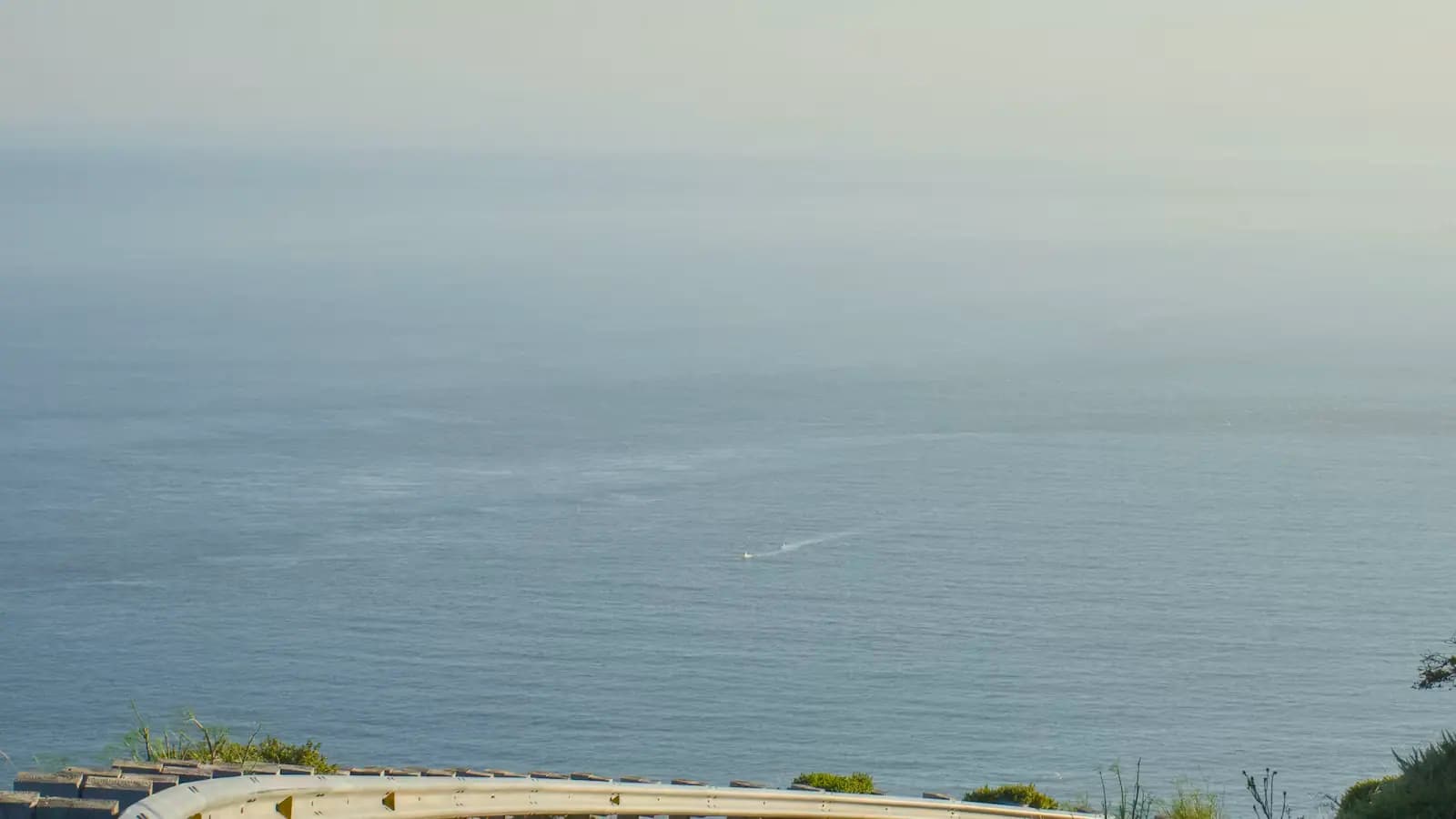 A curving coastal road running beside open water on a clear day